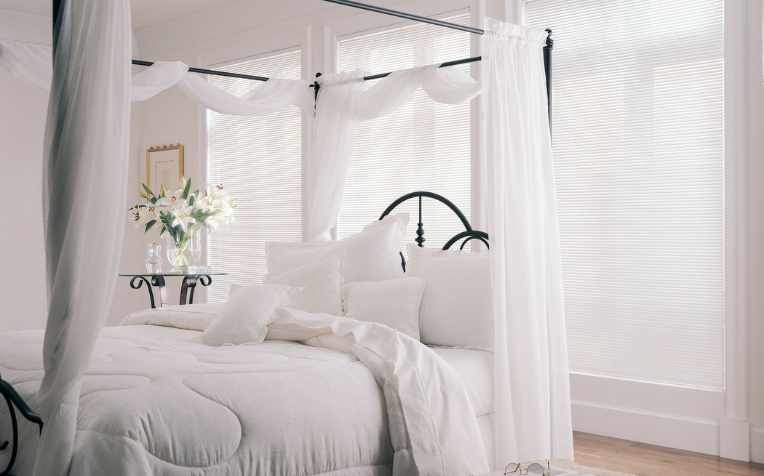 airy white, sheer curtains in all-white bedroom with canopy bed